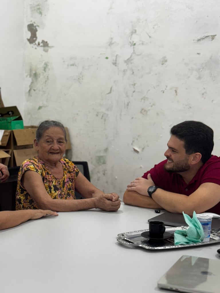 André Martha conversa com uma mulher idosa durante um encontro comunitário